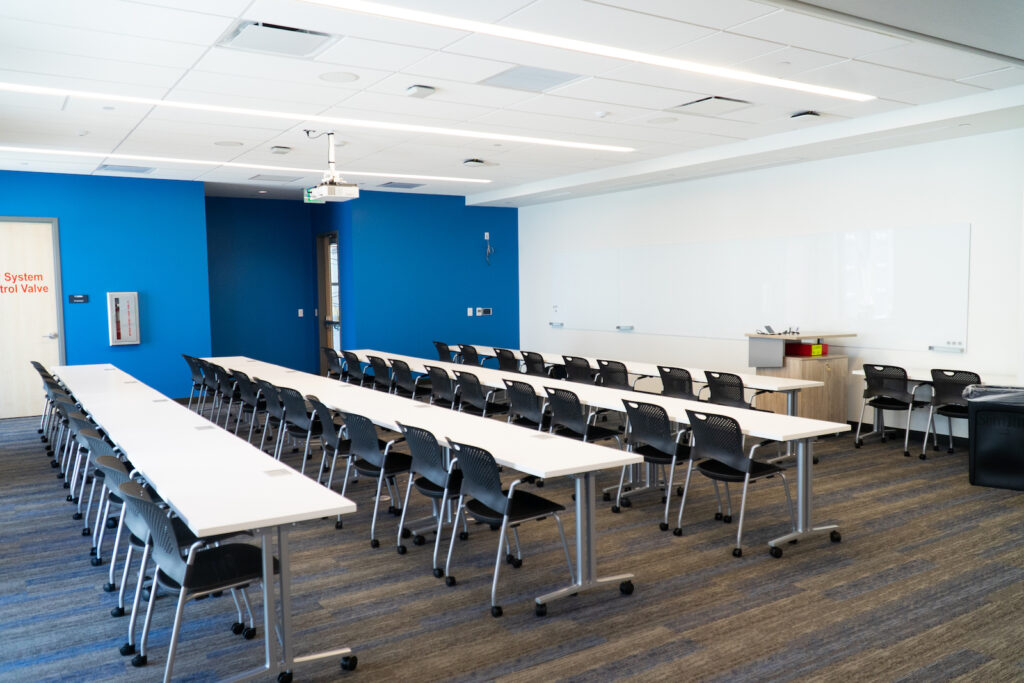 Classroom space with four long tables and a large white board on one wall.