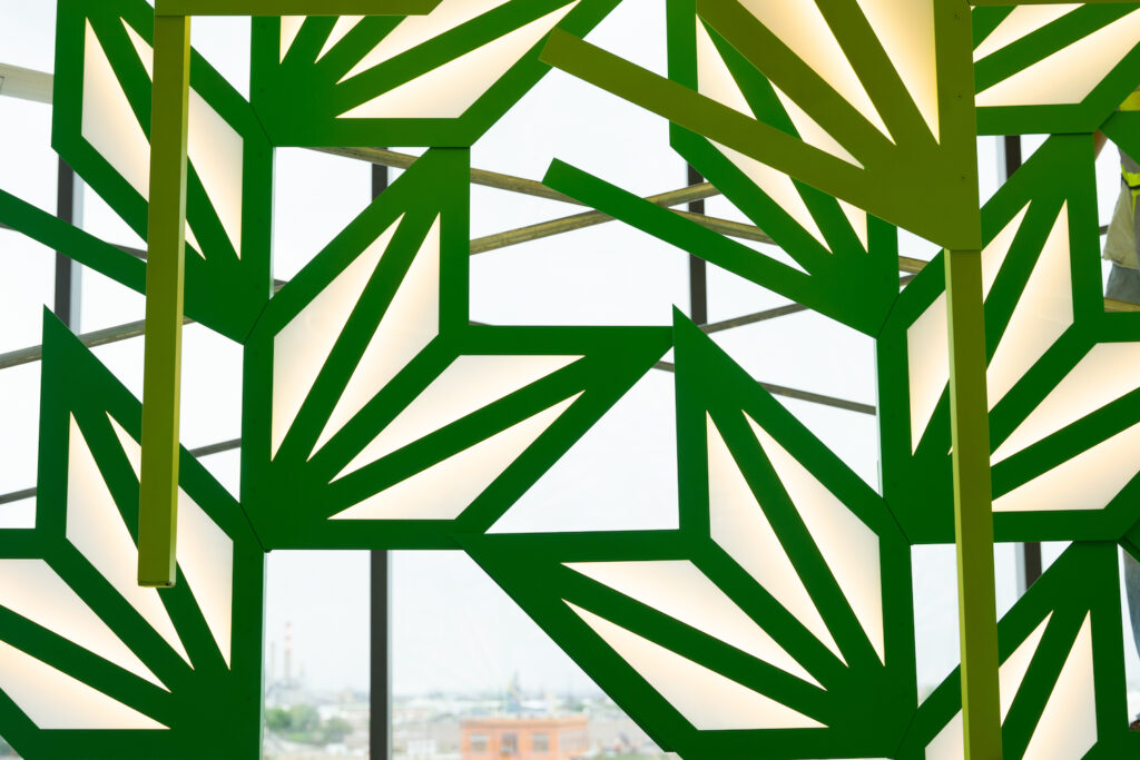 Close up view of green geometric leaf shapes that make up a hanging art installation.