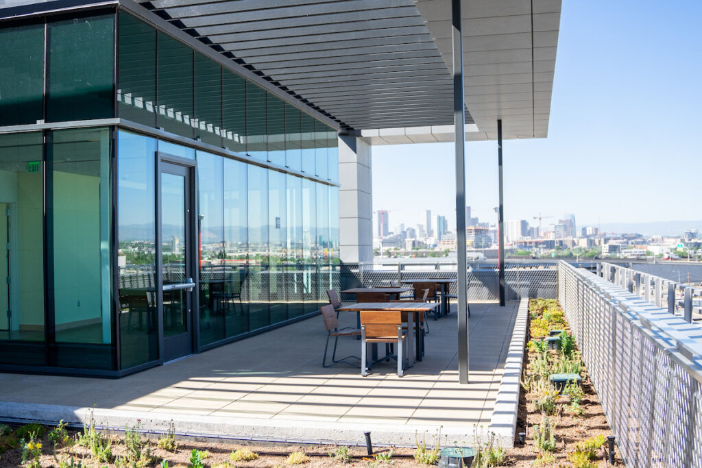 Outdoor terrace with tables and chairs and a view of the Denver skyline.