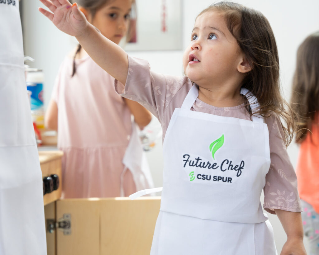 A young girl wearing an apron that says "future chef."