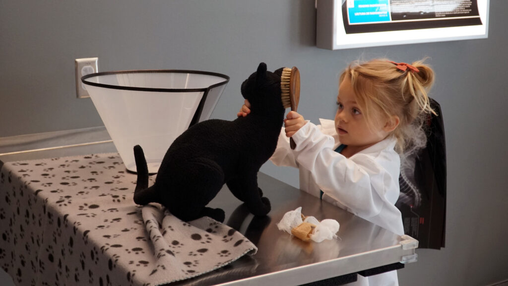 A child brushes a plush cat stuffed animal.