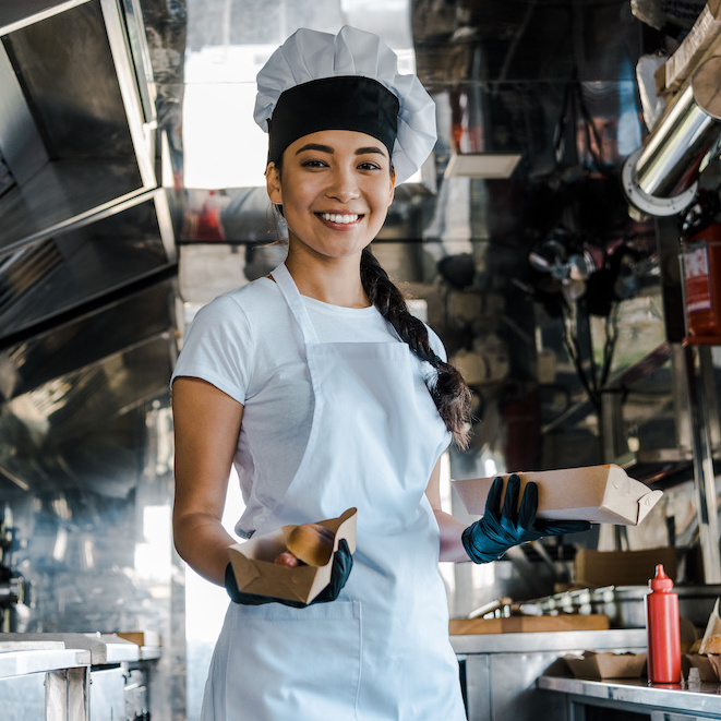 Woman in a chef's hat in the interior of a food truck.
