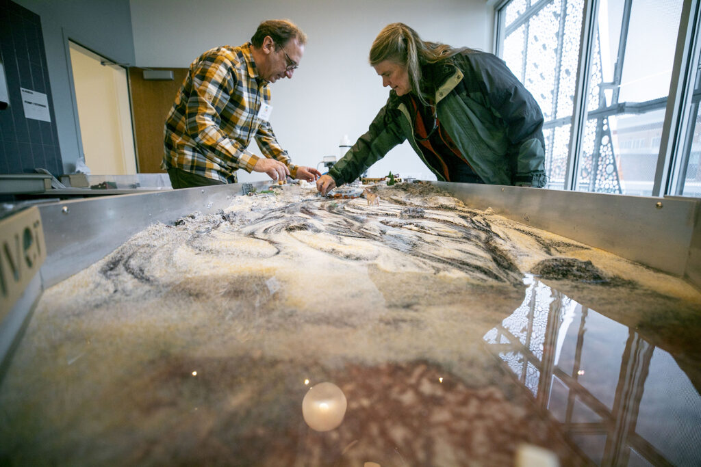 Two people interact with a stream table.