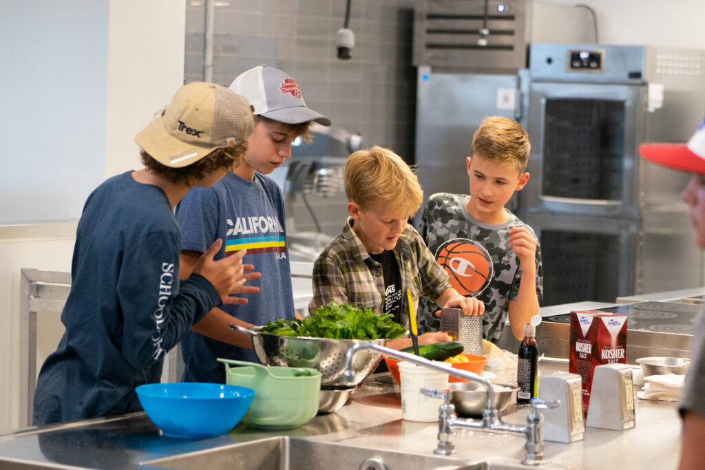 Four young people work in a kitchen together.