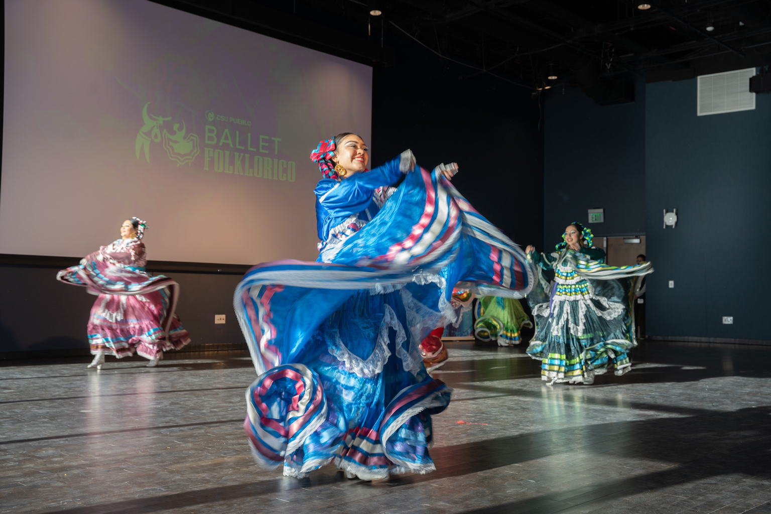 Dancers in colorful outfits dance on a stage.