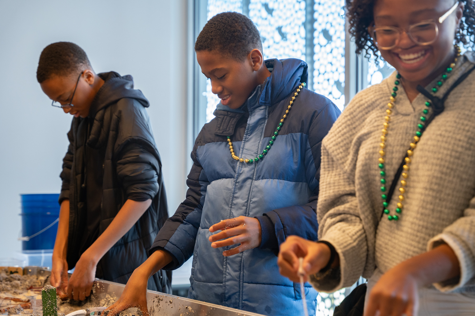Three kids interact with a stream table.
