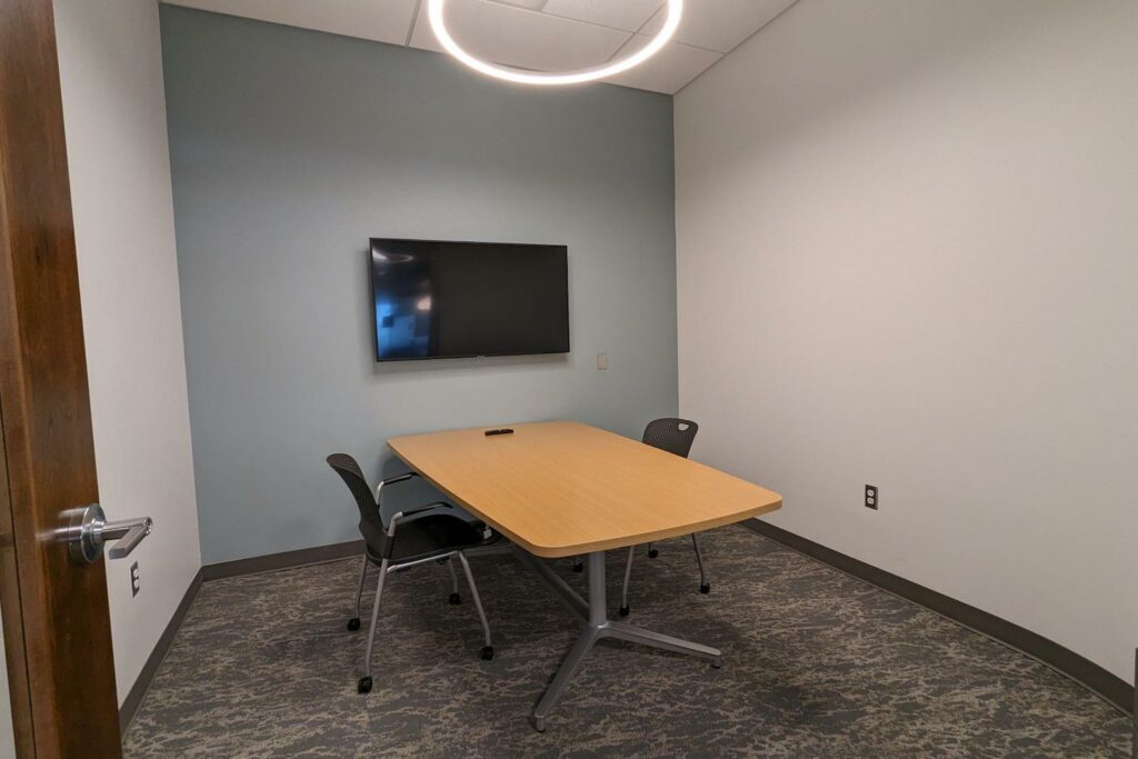 Conference room with a table and a wall-mounted TV.