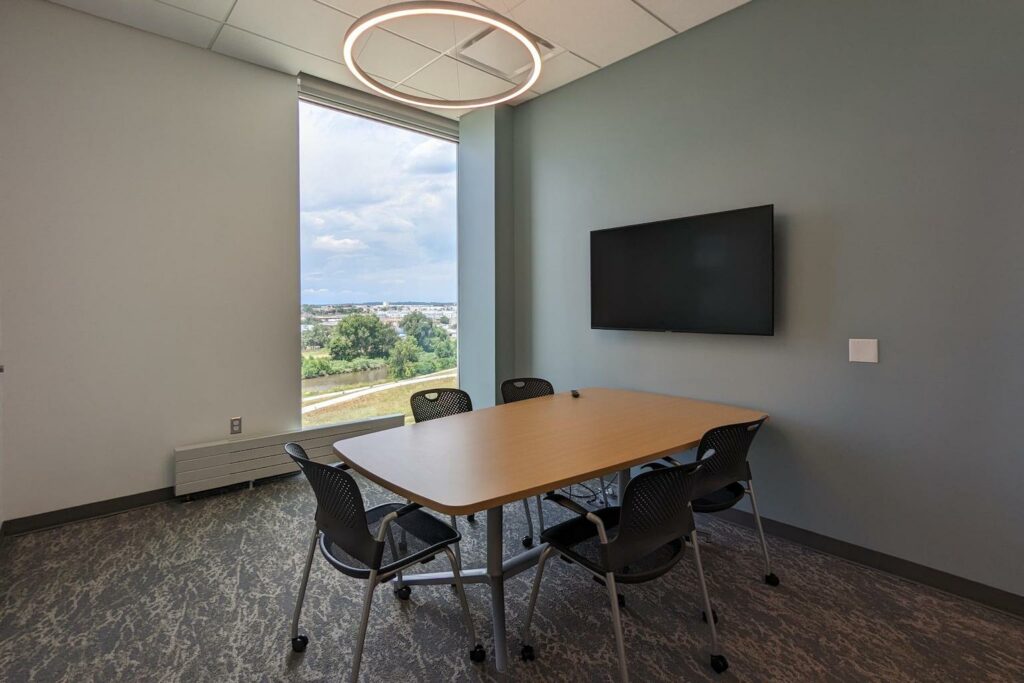 Conference room with a 6-seater table and a wall-mounted TV.