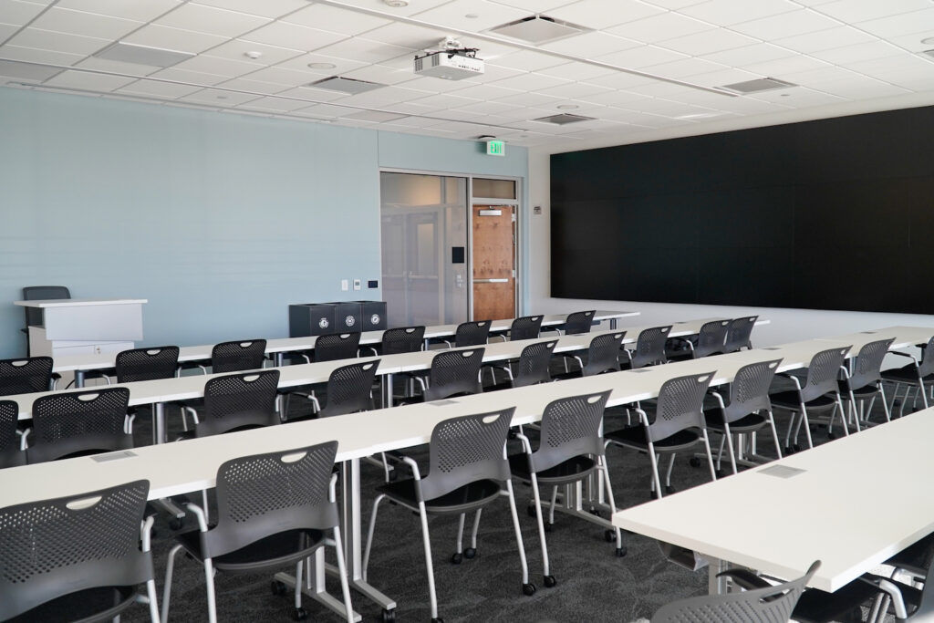 Classroom space with rows of desks and a large screen.