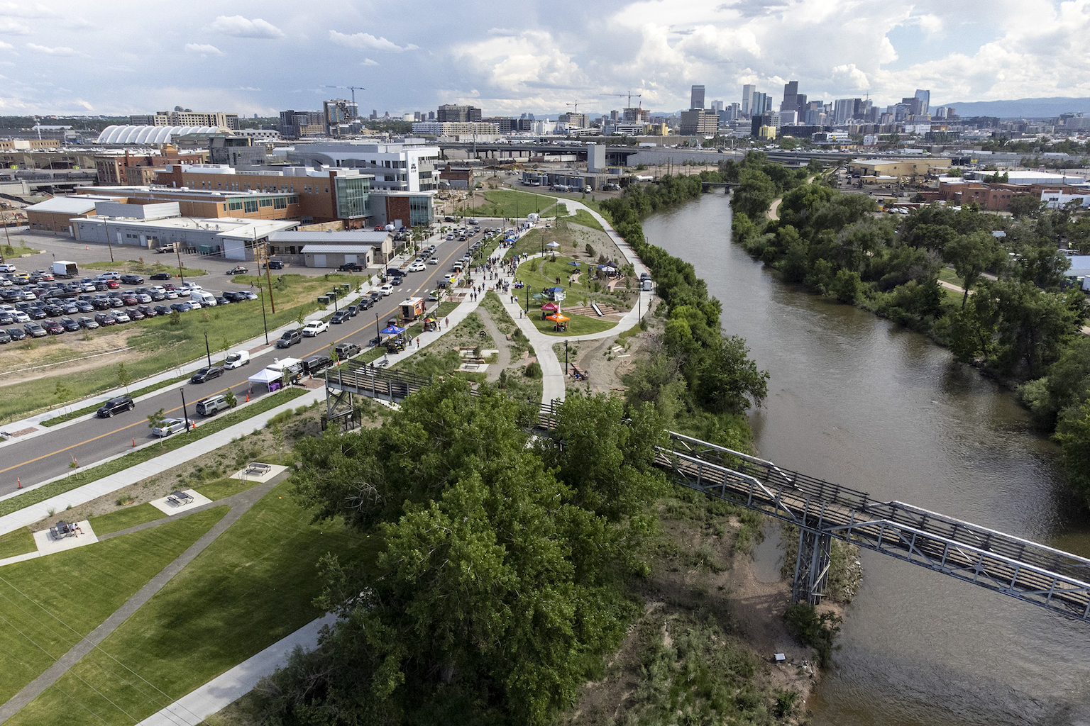 Aerial view of a riverfront space with the Denver skyline in the background.