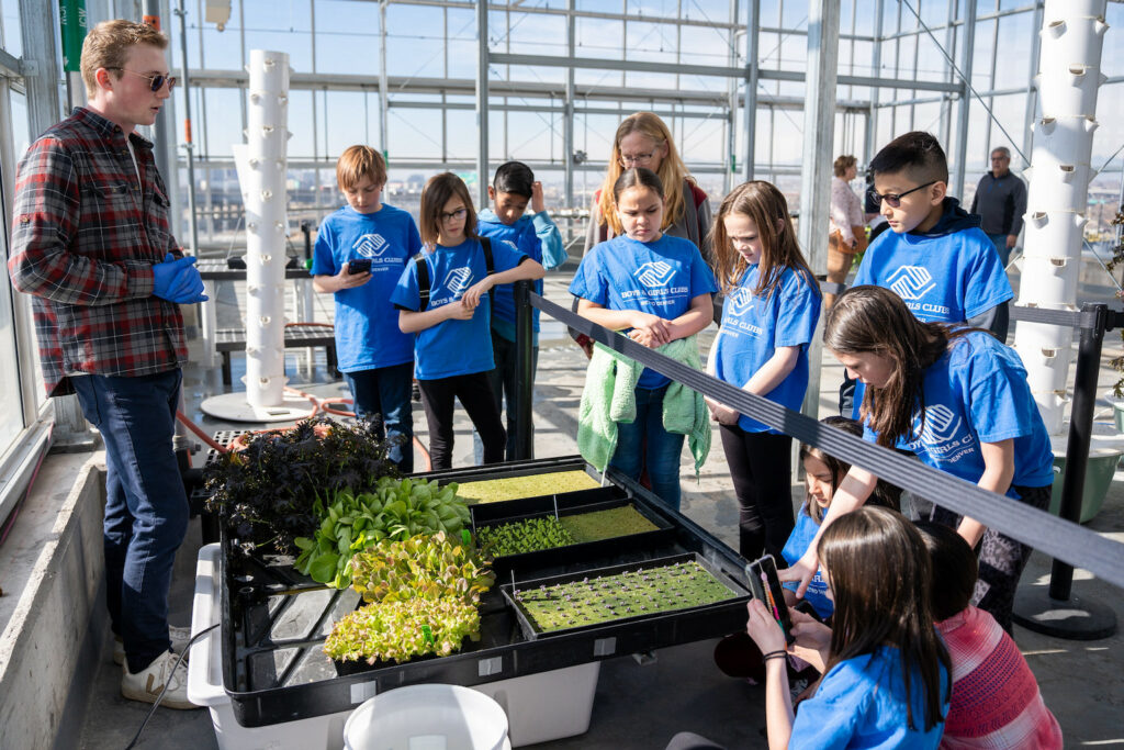 A group of students gathers in a greenhouse.