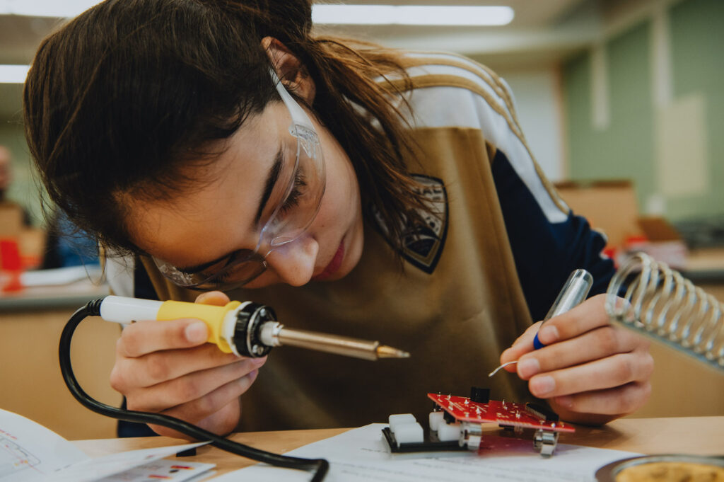 A student looks carefully at a circuit board.