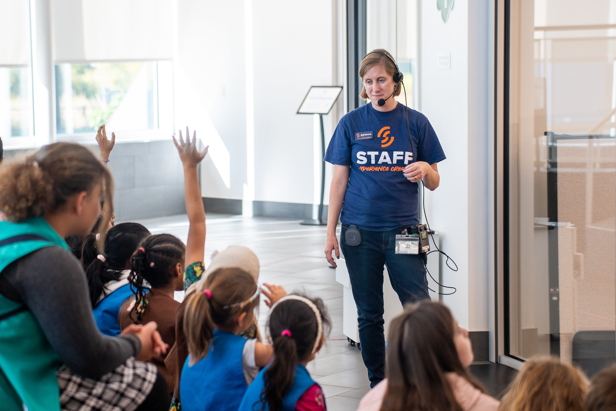 A group of kids listens to an instructor with a headset.