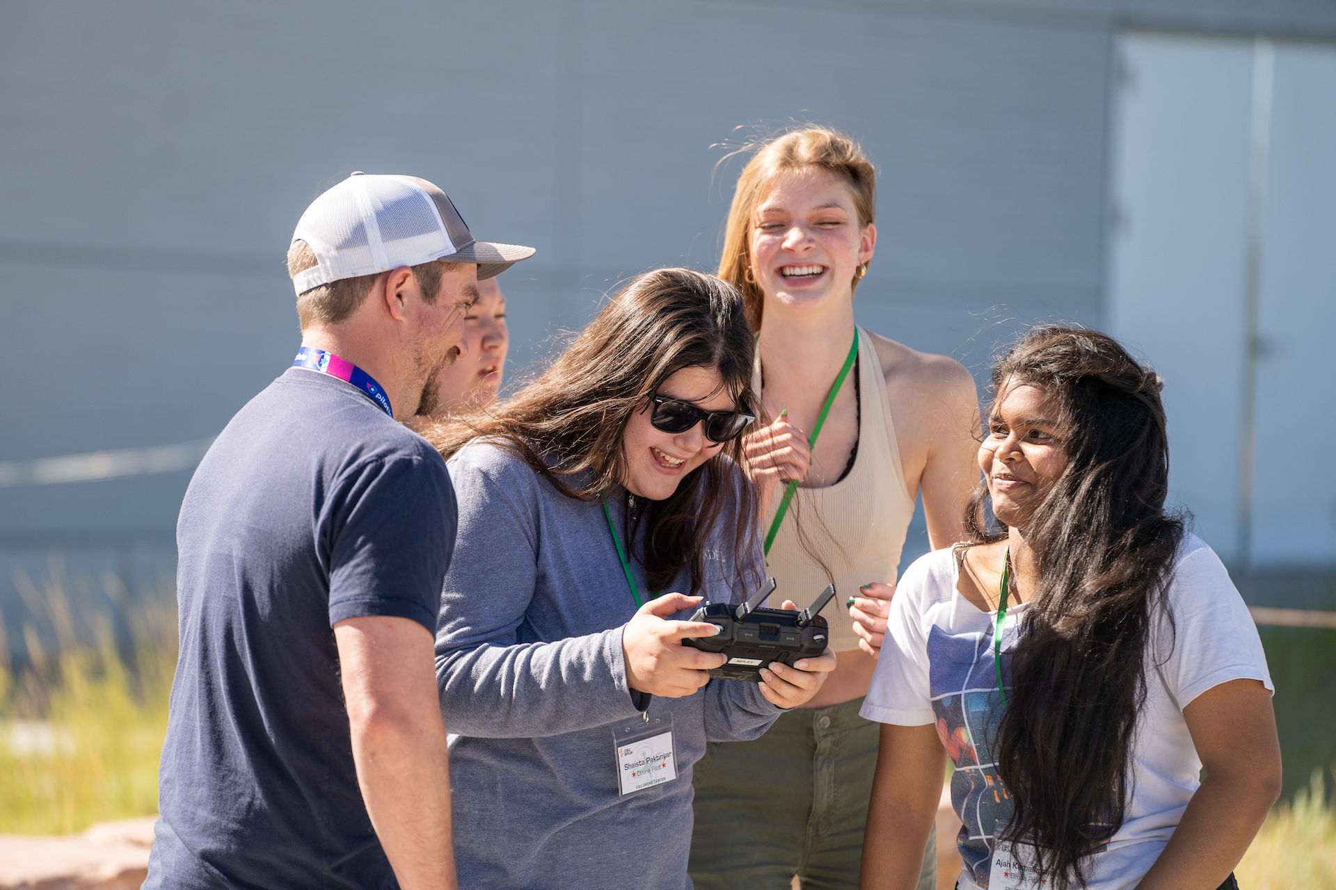 Students gather around another student operating a drone remote.