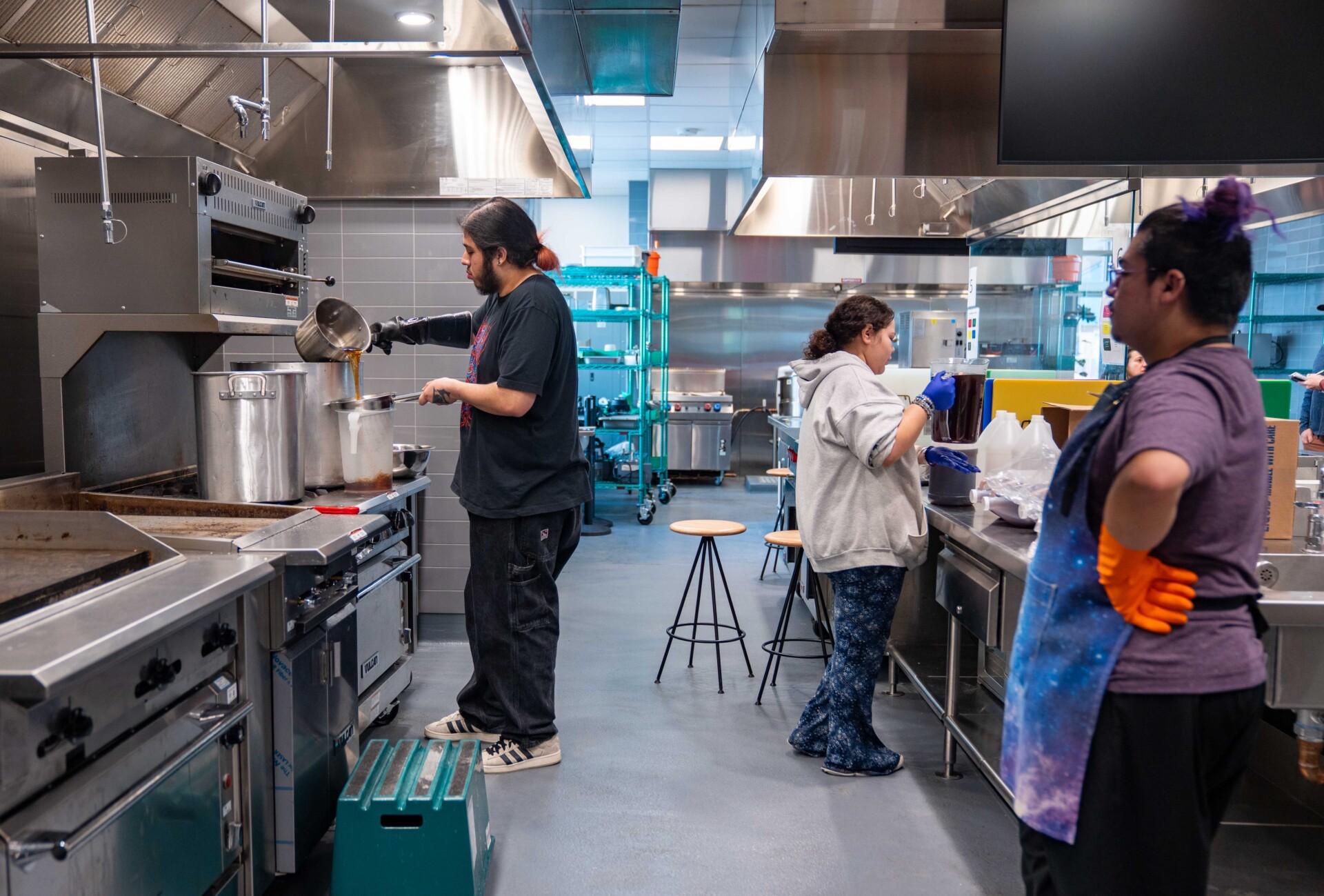 Three people working in an industrial kitchen.