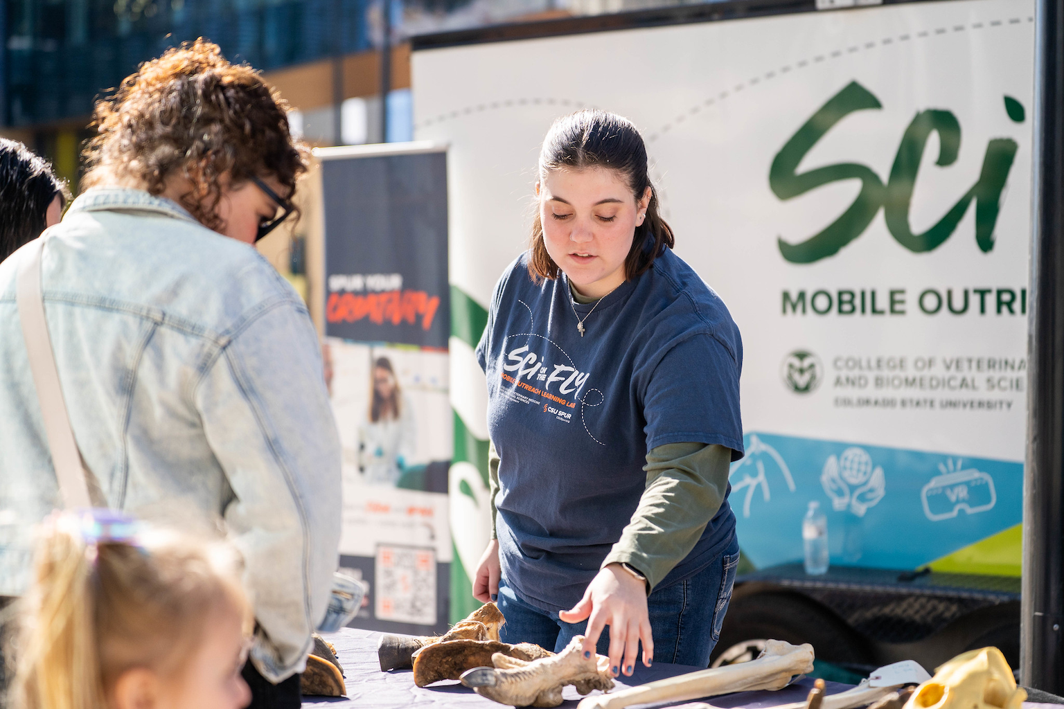 A person in a Sci on the Fly t-shirt talks to a table visitor.