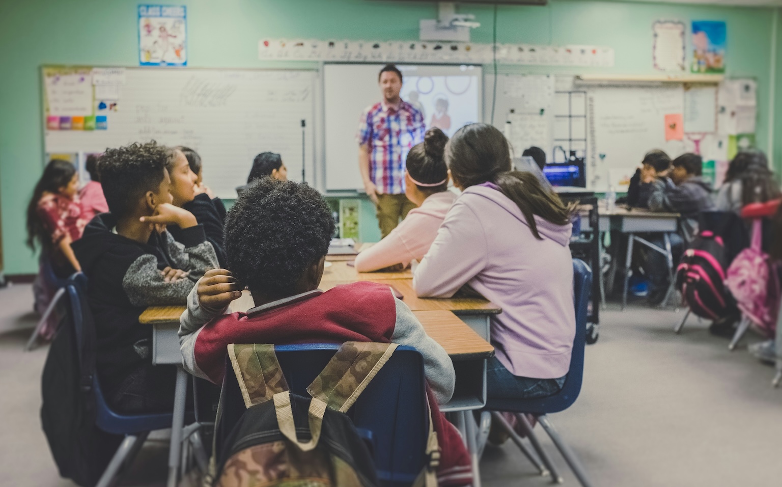 A teacher stands in front of a room of students.