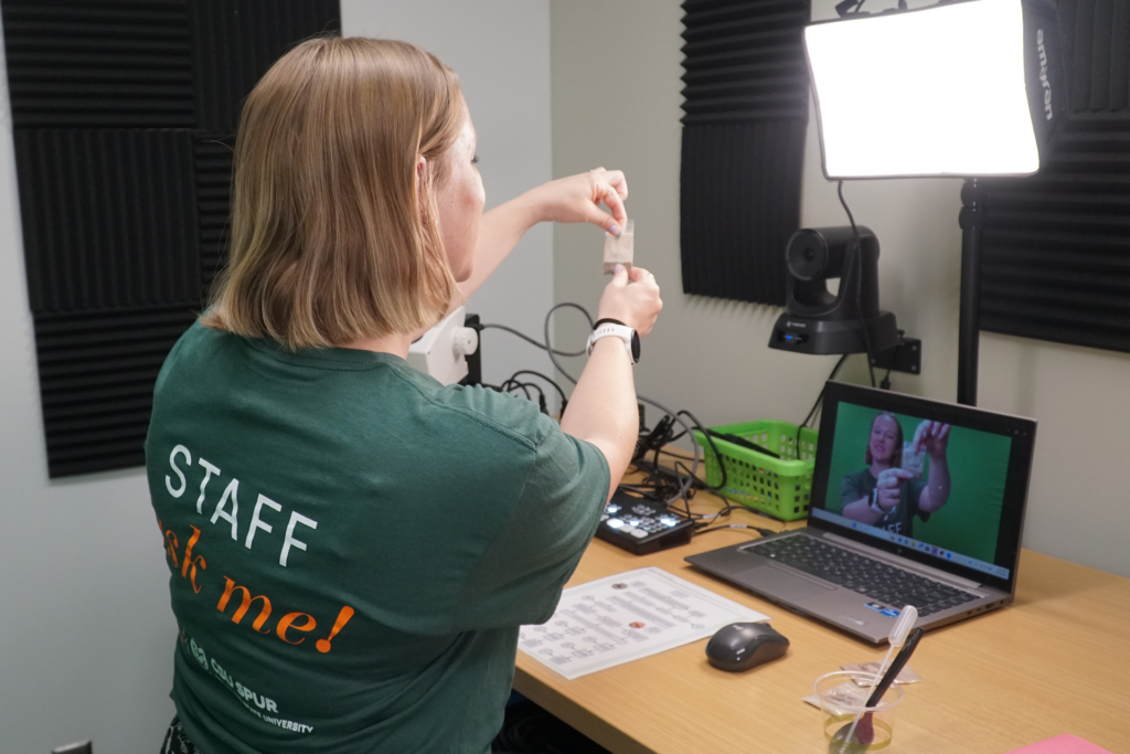 A woman in a Spur staff t-shirt demonstrates something on a screen.